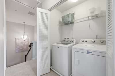 Conveniently located laundry area features modern appliances and practical shelving for organized storage.