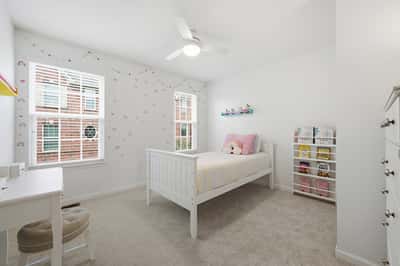 Bright and airy bedroom with ample natural light, featuring a cozy bed and playful decor.