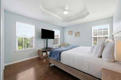 Bright and inviting bedroom featuring large windows, a modern ceiling fan, and ample space for relaxation.