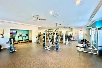 Spacious fitness center featuring diverse exercise equipment and ample natural light for an invigorating workout experience.