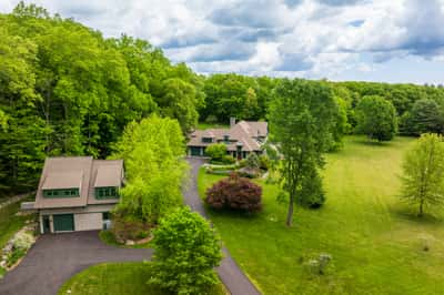 Expansive property surrounded by lush greenery, featuring spacious living areas and a convenient detached garage.