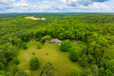 Expansive property surrounded by lush trees, featuring a spacious home and ample outdoor space for recreation.
