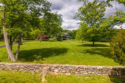 Spacious, verdant property featuring a welcoming home surrounded by mature trees and expansive lawns. Ideal for gatherings.