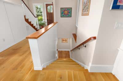 Bright entryway featuring hardwood floors and a welcoming staircase, leading to open living spaces.