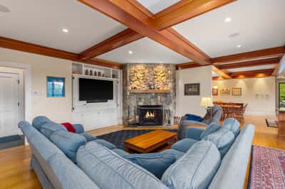 Cozy living area featuring a stone fireplace, wooden beams, and ample natural light for gatherings.