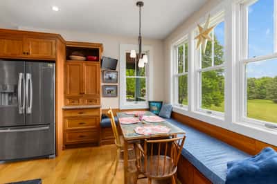 Bright kitchen with ample seating, large windows offering scenic views, and rich wooden cabinetry.