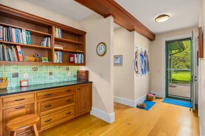 Bright and functional entryway featuring built-in shelving, a work area, and easy access to outdoor space.