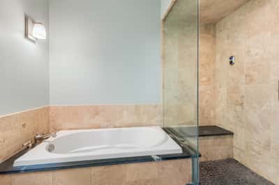 Discover a modern bathroom featuring a spacious soaking tub and a sleek, glass-enclosed shower area.