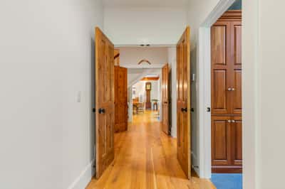 Spacious hallway featuring rich wood doors and natural light, leading to inviting living and dining areas.
