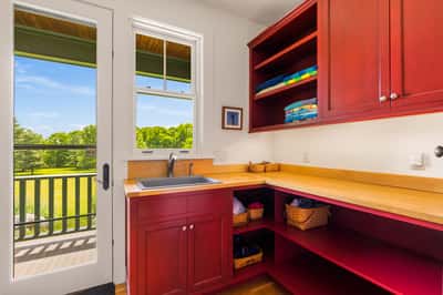 Bright and airy laundry room with outdoor access and scenic views, featuring ample storage for organization.