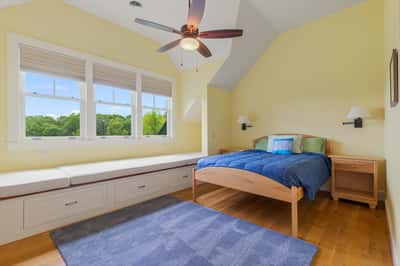 Bright bedroom featuring large windows, a cozy seating nook, and ample natural light throughout.