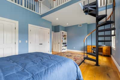 Spacious bedroom featuring a lofted area and a unique spiral staircase, ideal for versatile living.