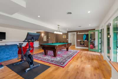 Spacious recreational room featuring a billiards table, exercise bike, and large windows for natural light located in the walkout basement