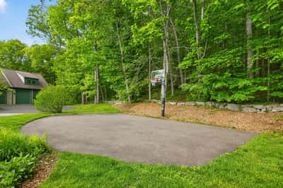 Spacious outdoor basketball area surrounded by lush greenery, perfect for active lifestyles and family fun.