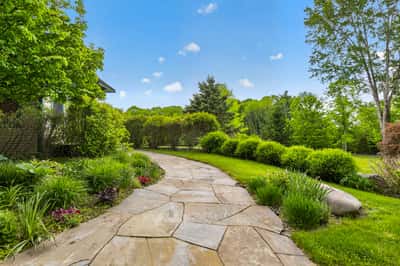 This inviting pathway leads through vibrant landscaping, showcasing a lush, green outdoor retreat ready for enjoyment.