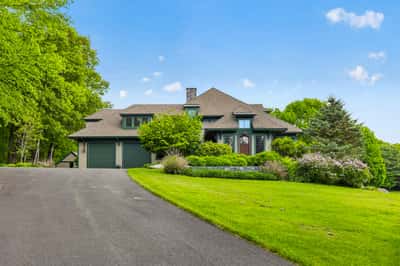 Spacious home surrounded by lush greenery, featuring an inviting driveway and ample outdoor space for recreation.
