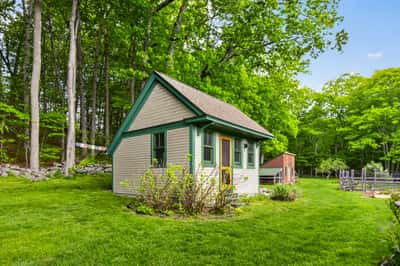 Cozy cottage surrounded by lush greenery, offering a peaceful retreat and ample outdoor space for relaxation.