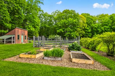 Discover a beautifully landscaped outdoor space featuring raised garden beds and a spacious shed amid lush greenery.