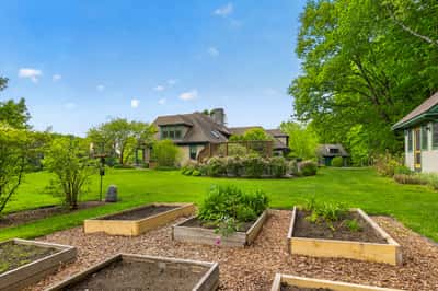 Spacious property featuring well-maintained gardens, expansive lawn, and a versatile outdoor space for recreation.
