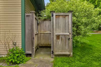 Discover this private outdoor shower, nestled between lush greenery and rustic wooden fencing for ultimate relaxation.