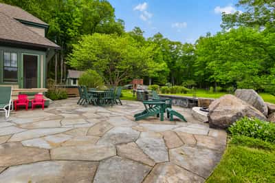 Spacious outdoor patio featuring natural stone, perfect for gatherings amidst lush greenery and tranquil surroundings.