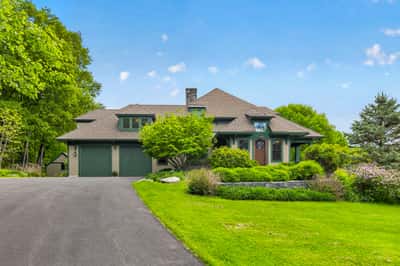 This spacious home features a unique architectural design, surrounded by lush landscaping and ample outdoor space.