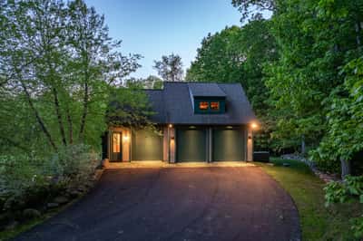 This inviting home features a three-car garage, surrounded by lush greenery for a private retreat feel.