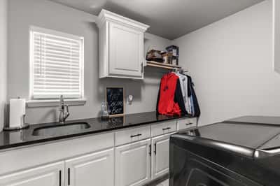 This well-appointed laundry area features modern cabinetry, sleek countertops, and convenient shelving for organization.