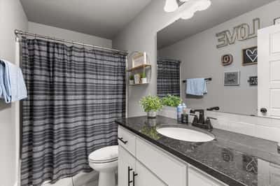Modern bathroom featuring a sleek black countertop and a tub shower combo.