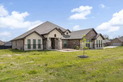 Spacious home with ample outdoor space and distinctive stone accents, perfect for family living and entertaining.