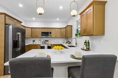 Modern kitchen featuring warm wood cabinetry, spacious countertops, and seating for casual dining. Ideal for entertaining.