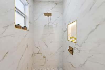This luxurious shower features stunning marble tile, a rain showerhead, and a convenient built-in niche for storage.