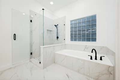 Modern bathroom featuring a glass shower, soaking tub, and sleek marble accents for a luxurious experience.