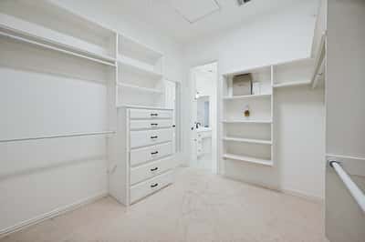 Primary bedroom spacious walk-in closet features ample storage, organized shelving, and convenient access to an adjoining bathroom.