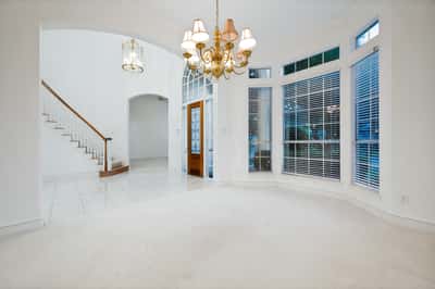 Bright and inviting living space featuring large windows, high ceilings, and an open staircase layout.