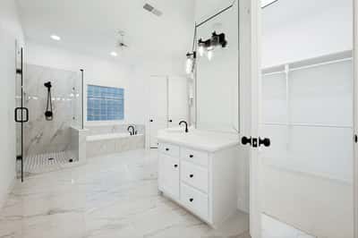 Spacious primary bathroom featuring modern fixtures, a luxurious tub, and ample storage in a sleek design.
