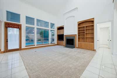 Spacious living area featuring large windows and built-in shelving, perfect for natural light and personal decor.