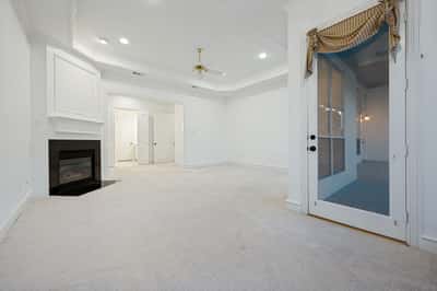 Spacious primary bedroom featuring a cozy fireplace and seamless access to a private sitting area.