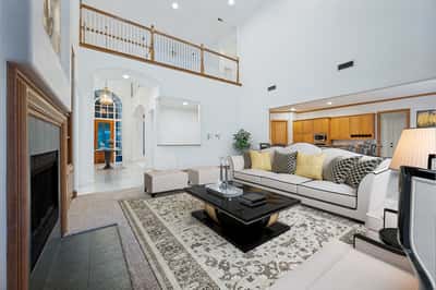Spacious living room featuring high ceilings, natural light, and modern furnishings, perfect for entertaining or relaxation.