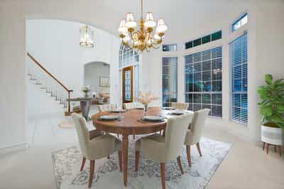 Bright and inviting dining area, featuring large windows, a beautiful chandelier, and a welcoming atmosphere.