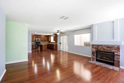 Spacious living area with hardwood floors and a cozy fireplace, seamlessly connected to a modern kitchen.