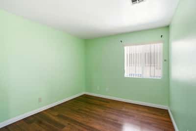 Bright and inviting room featuring fresh green walls and modern hardwood flooring, perfect for personalization.
