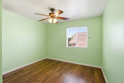 Bright, airy room with a ceiling fan, large window, and fresh paint, ideal for versatile use.