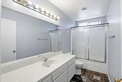 Bright and spacious bathroom featuring dual sinks, modern fixtures, and a large walk-in shower.