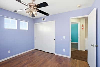 Bright and airy bedroom featuring a ceiling fan and convenient double-door closet for ample storage.