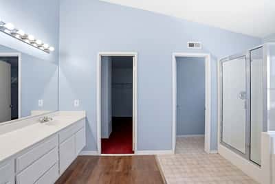 Bright and spacious bathroom featuring modern fixtures, dual vanities, and a convenient walk-in closet.