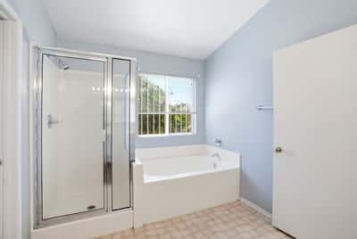 Bright and spacious bathroom featuring a separate shower, soaking tub, and natural light from large window.