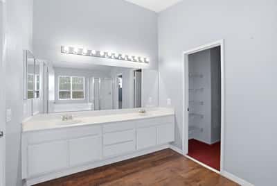 Bright and spacious master bathroom featuring dual vanities, modern lighting, and ample storage options.