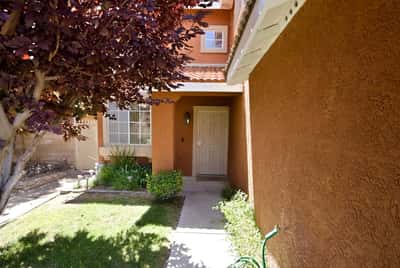 Inviting entryway leading to a cozy home, surrounded by lush greenery and vibrant landscaping.
