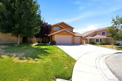 Spacious two-story home with a large yard, driveway, and vibrant landscaping in a quiet neighborhood.